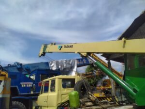 Pemasangan Sticker Cutting logo Tadano pada lengan crane alat berat di sebuah proyek di Bali
