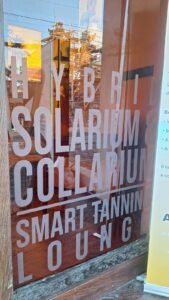 Pemasangan Sticker Cutting pada etalase kaca bisnis tanning di Bali dengan desain tipografi yang elegan dan minimalis.