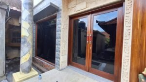 Pemasangan kaca film gelap pada pintu dan jendela rumah tradisional Bali