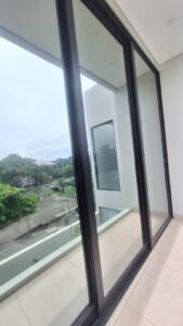 Kaca film bening anti panas pada pintu geser kaca gedung modern di Bali