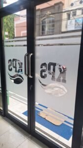 Sticker Sandblast custom logo KPS pada kaca pintu masuk toko di Bali