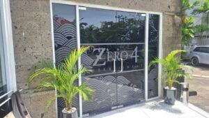Sticker Sandblast motif ombak Jepang dan logo Zero 4 Entertainment pada kaca pintu masuk gedung di Bali