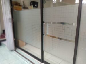 Sticker Sandblast motif kotak-kotak grid kombinasi garis clear pada kaca pintu toko di Bali