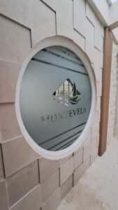 Sticker Sandblast custom logo Montevela pada kaca jendela oval dinding batu elegan di Bali