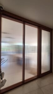 Sticker Sandblast motif garis vertikal halus full panel pada kaca pintu geser bingkai kayu di Bali