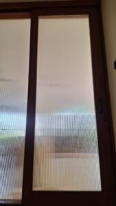 Sticker Sandblast motif garis vertikal halus close-up pada kaca pintu geser bingkai kayu di Bali