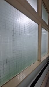 Sticker Sandblast motif kotak-kotak grid close-up pada kaca jendela fasilitas kesehatan di Bali