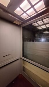 Sticker Solid warna abu-abu muda pada dinding interior lift dengan panel kaca di Bali