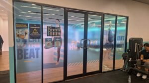 Sticker Print frosted branding Fit Hub gym dengan motif motivasi olahraga di kaca partisi studio Bali