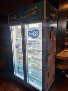Sticker Print branding RON88 air mineral pada kulkas display di restoran Bali