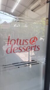 Cutting sticker merah logo Lotus Desserts pada pintu kaca toko dessert