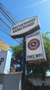 Cutting sticker Brotherhood Barbershop dan Free WiFi pada neon box pinggir jalan