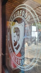 Detail cutting sticker sandblast logo pria berjenggot Brotherhood Barbershop pada kaca