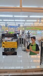 Cutting sticker informasi toko dan jam buka pada pintu kaca minimarket Ayu Nadi Raya Kuta