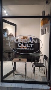 Cutting sticker putih logo Urban Cult Shoes Care Repair Helmet pada pintu kaca toko