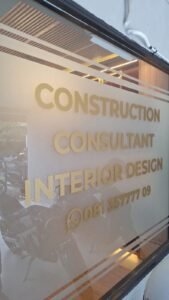 Cutting sticker emas tulisan Construction Consultant Interior Design pada kaca kantor