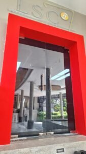 Kaca film pada pintu kaca frameless double dengan kusen merah di pintu masuk gedung LSC Billiard