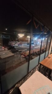 Kaca film gelap pada jendela kaca restoran dengan pemandangan jalan di malam hari