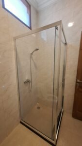 Kaca film pada shower box kaca kamar mandi rumah dengan dinding keramik marmer