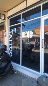 Kaca film hitam dan cutting sticker Four Leaf Tattoo Studio pada etalase kaca toko