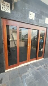 Kaca film pada pintu kaca lipat kusen kayu dilihat dari teras rumah