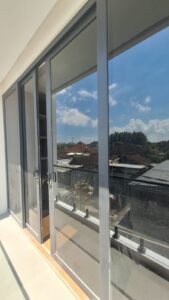 Kaca film pada pintu kaca geser kusen aluminium di balkon lantai atas