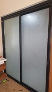 Sticker sandblast pada pintu kaca geser kamar mandi kusen aluminium hitam