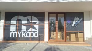 Sticker print logo Mykood dan grafis produk pada kaca depan toko